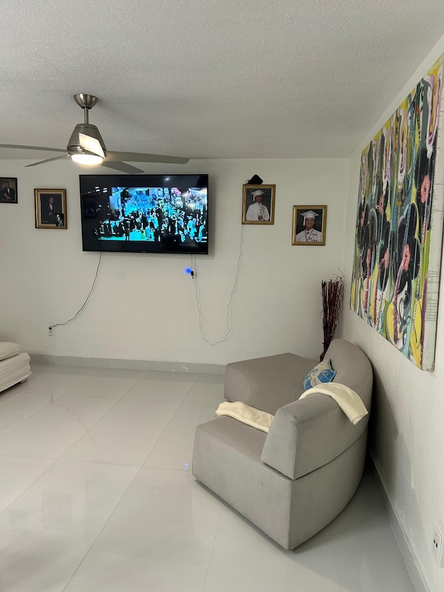 living area with a ceiling fan and a textured ceiling