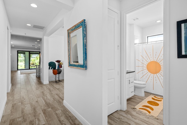 corridor with light wood-style floors, baseboards, recessed lighting, and visible vents