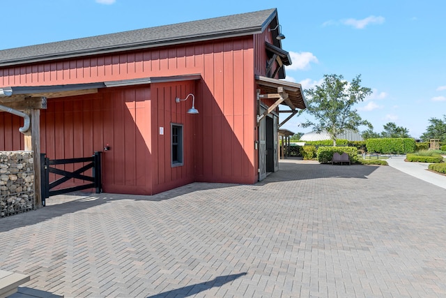 exterior space with board and batten siding and roof with shingles