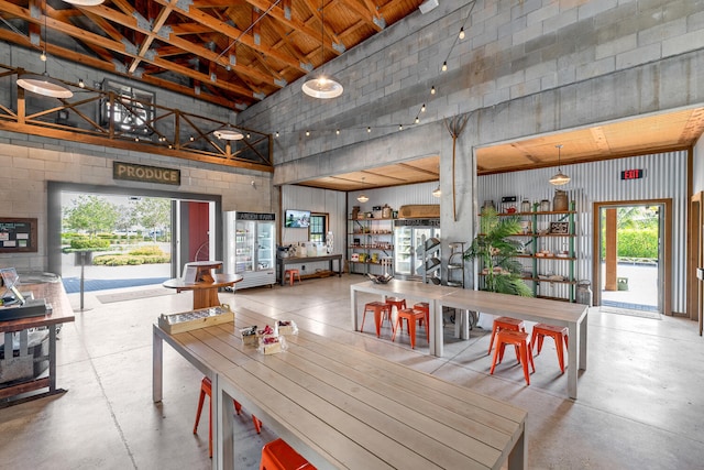 dining space featuring a high ceiling and concrete flooring