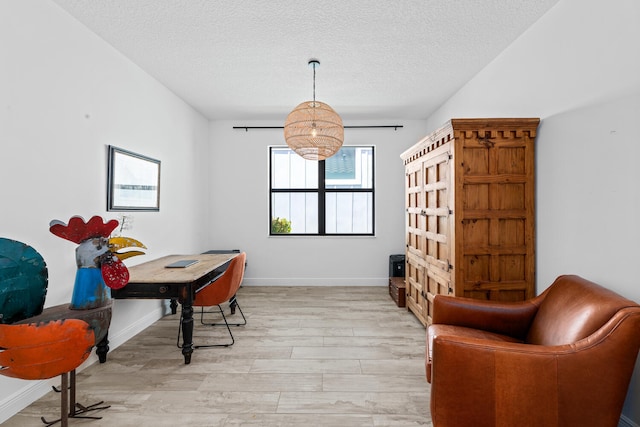 interior space with baseboards, a textured ceiling, light wood finished floors, and an inviting chandelier