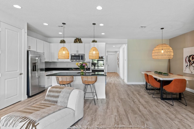 kitchen with dark countertops, light wood-style floors, baseboards, white cabinetry, and appliances with stainless steel finishes