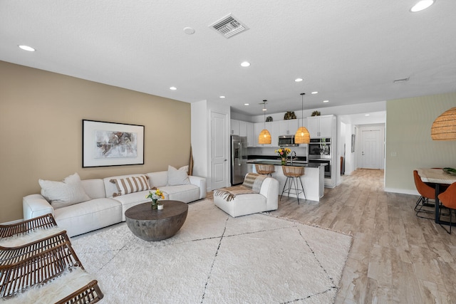 living area featuring visible vents, recessed lighting, light wood-style floors, and baseboards