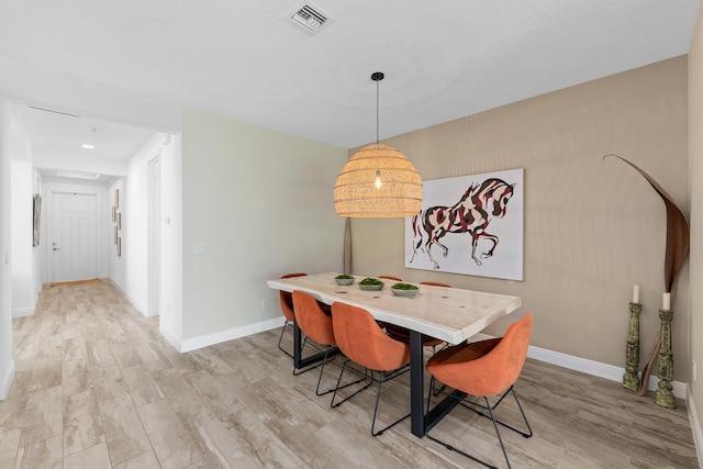 dining room featuring visible vents, light wood-style floors, and baseboards