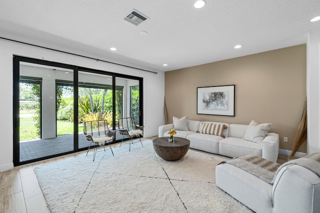 living room with recessed lighting, baseboards, visible vents, and a textured ceiling
