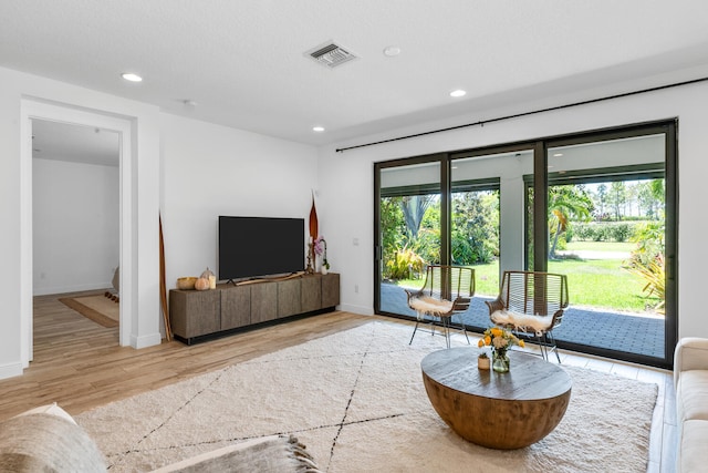 living area with recessed lighting, baseboards, light wood-type flooring, and visible vents