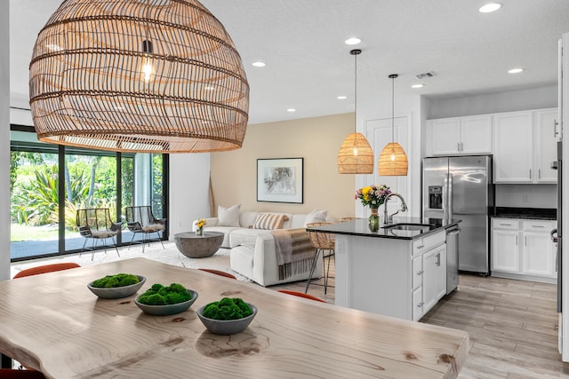 kitchen with visible vents, dark countertops, a sink, open floor plan, and stainless steel appliances