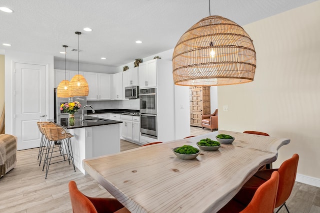 kitchen featuring dark countertops, a breakfast bar, recessed lighting, a sink, and appliances with stainless steel finishes