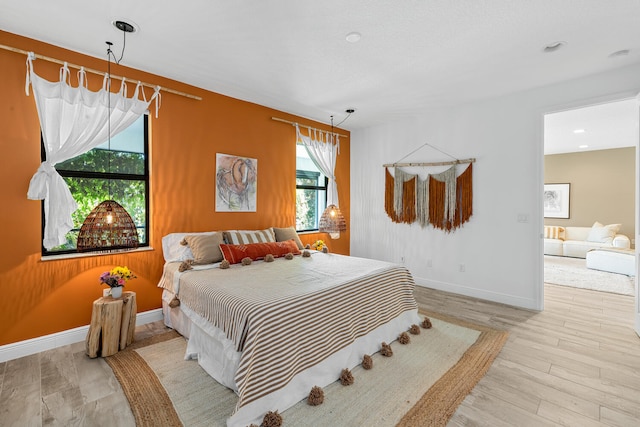 bedroom featuring baseboards, wood finished floors, and multiple windows