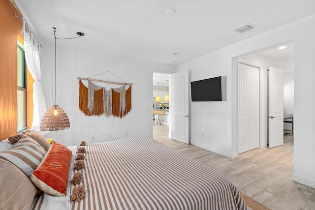 bedroom featuring multiple windows, a closet, light wood finished floors, and visible vents