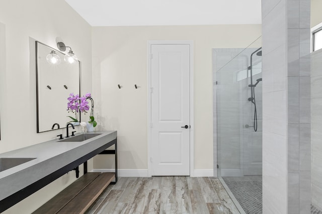 bathroom with baseboards, wood finished floors, vanity, and a shower stall