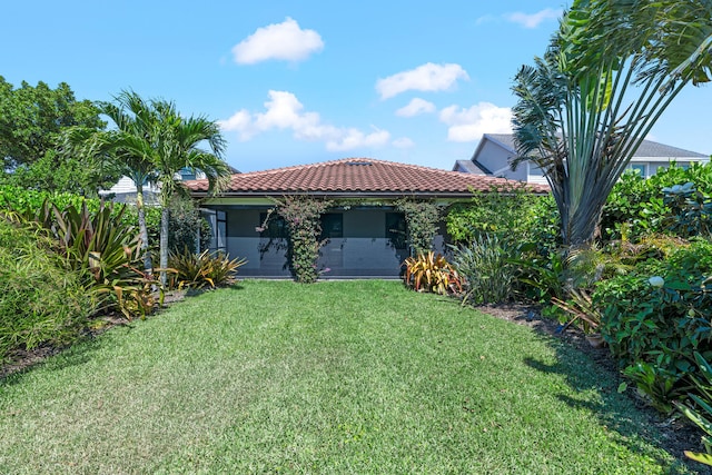 rear view of property featuring a tiled roof and a lawn