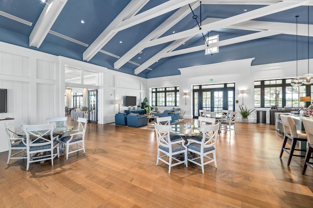dining room featuring a decorative wall, beam ceiling, and high vaulted ceiling