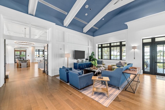 living room featuring wood-type flooring, a decorative wall, beam ceiling, and a wealth of natural light