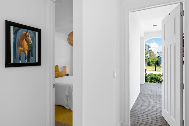 corridor featuring baseboards and brick floor