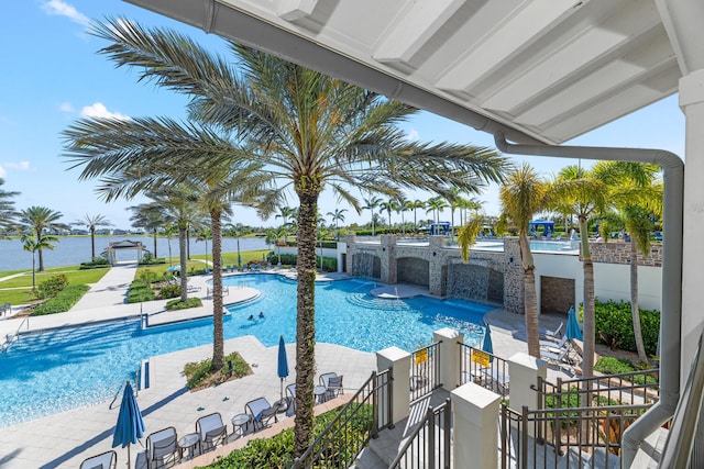 pool with a water view, fence, and a patio area