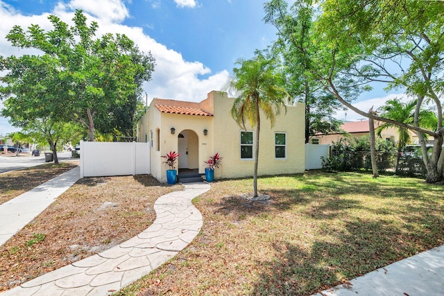 5900 Garden Ave, West Palm Beach, FL 33405 - mediterranean / spanish-style home featuring a front yard, stucco siding, a tile roof, and fence