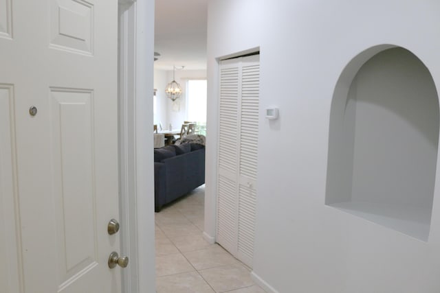 12582 Shoreline Dr, Wellington, FL 33414 - hallway with arched walkways, baseboards, an inviting chandelier, and light tile patterned floors