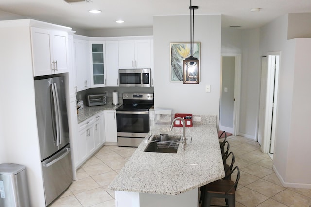 12582 Shoreline Dr, Wellington, FL 33414 - kitchen with white cabinets, light tile patterned flooring, appliances with stainless steel finishes, a sink, and a kitchen bar