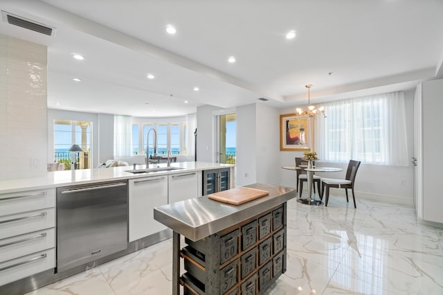 kitchen featuring stainless steel dishwasher, a sink, white cabinets, a chandelier, and recessed lighting