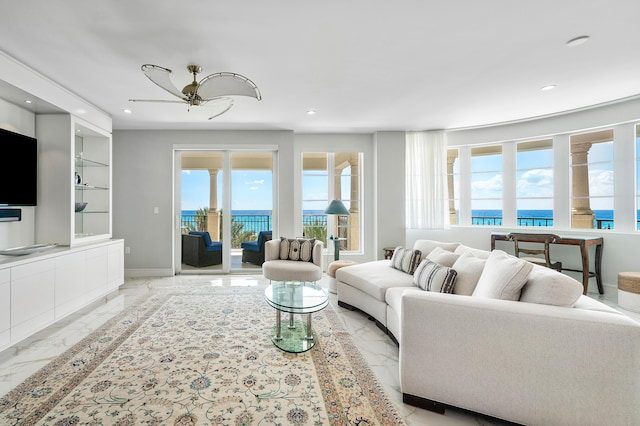 living room featuring light marble finish flooring, a water view, plenty of natural light, and recessed lighting