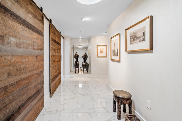 hallway with marble tiled floors, a barn door, and baseboards