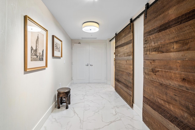 corridor with a barn door, light marble finish floors, baseboards, and wooden walls