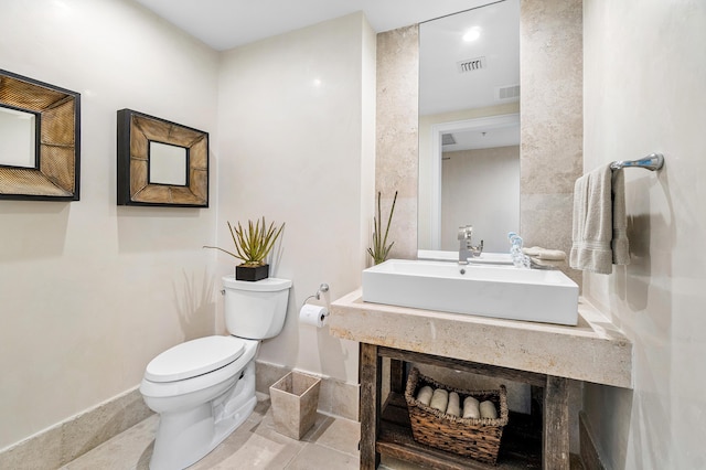 bathroom featuring toilet, a sink, and tile patterned flooring