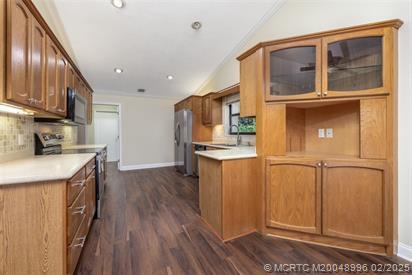 5361 SW Windward Way, Palm City, FL 34990 - kitchen featuring appliances with stainless steel finishes, backsplash, glass insert cabinets, light countertops, and baseboards