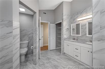 5361 SW Windward Way, Palm City, FL 34990 - full bathroom featuring marble look tile flooring, double vanity, toilet, and tile walls