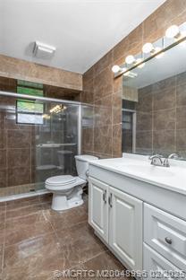 5361 SW Windward Way, Palm City, FL 34990 - full bath featuring tile walls, toilet, vanity, and a stall shower