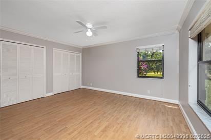 5361 SW Windward Way, Palm City, FL 34990 - unfurnished bedroom with ornamental molding, two closets, wood finished floors, baseboards, and ceiling fan