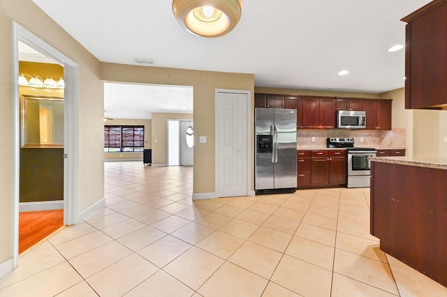 2602 SW 23rd Cranbrook Dr, Boynton Beach, FL 33436 - kitchen featuring stainless steel appliances, decorative backsplash, light tile patterned flooring, baseboards, and reddish brown cabinets