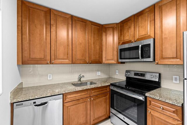 556 Mansfield N, Boca Raton, FL 33434 - kitchen with stainless steel appliances, a sink, backsplash, and brown cabinetry