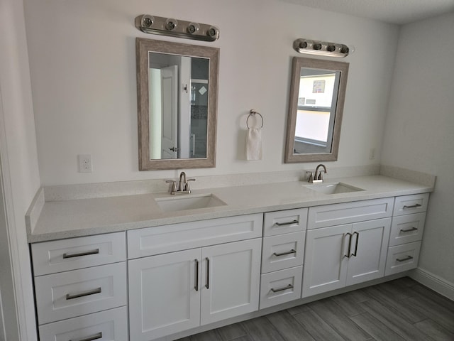 bathroom with double vanity, a sink, and wood finished floors