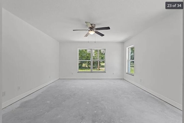 spare room with baseboards, a ceiling fan, and unfinished concrete floors