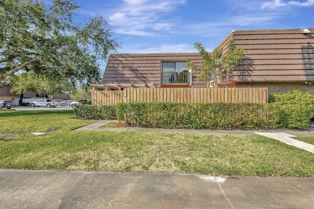 view of property exterior featuring a yard, mansard roof, and brick siding
