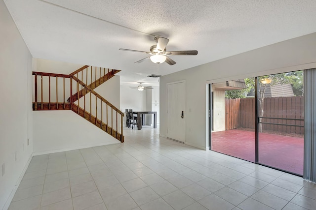 unfurnished living room with visible vents, stairs, ceiling fan, a textured ceiling, and tile patterned floors