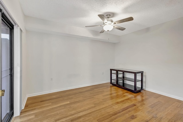 empty room featuring baseboards, a ceiling fan, light wood-style flooring, and a textured ceiling