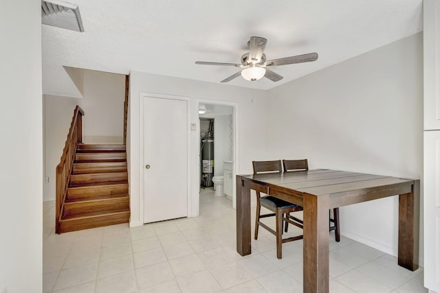 dining space with visible vents, a ceiling fan, stairs, and gas water heater