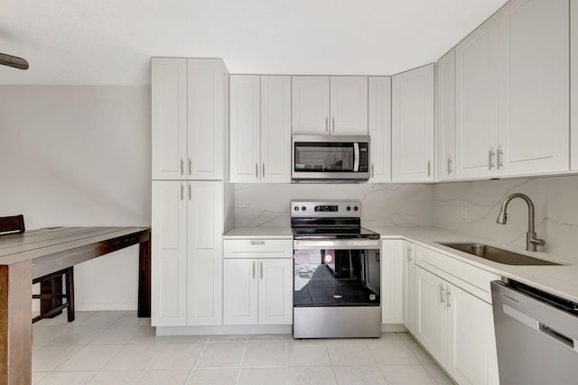 kitchen featuring backsplash, stainless steel appliances, white cabinetry, and a sink