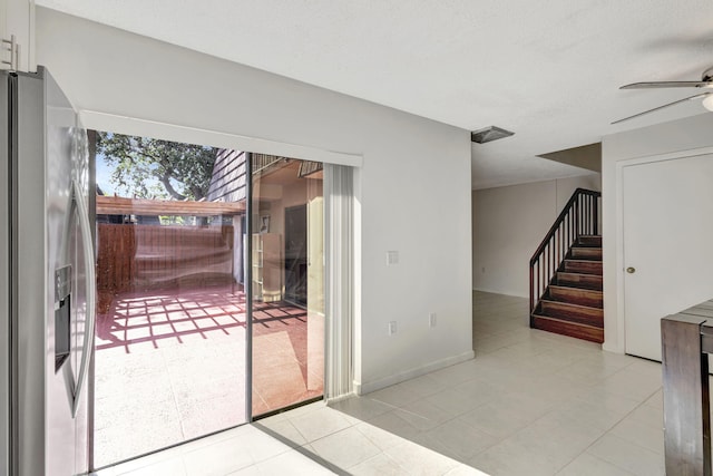 doorway to outside featuring ceiling fan, tile patterned floors, and stairway