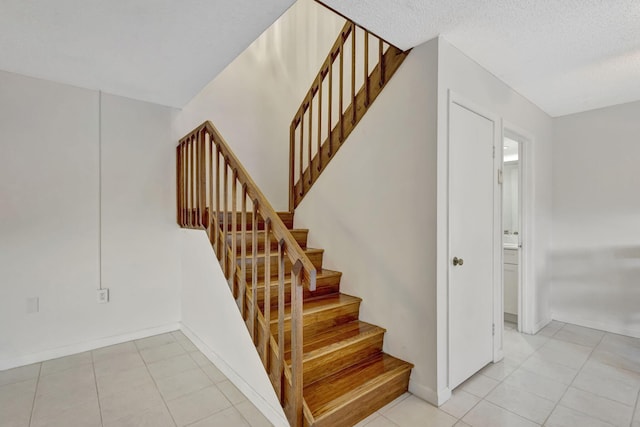 stairs with baseboards, tile patterned flooring, and a textured ceiling