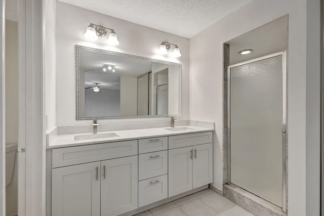 full bath featuring double vanity, a textured ceiling, a shower stall, and a sink