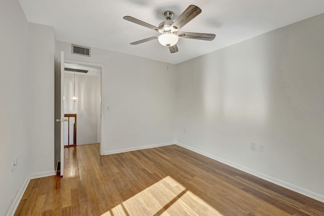 unfurnished room with visible vents, a ceiling fan, baseboards, and wood finished floors