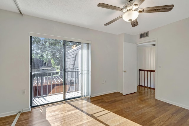 spare room featuring visible vents, a ceiling fan, baseboards, and wood finished floors