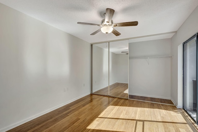 unfurnished bedroom with a ceiling fan, a textured ceiling, wood finished floors, baseboards, and a closet