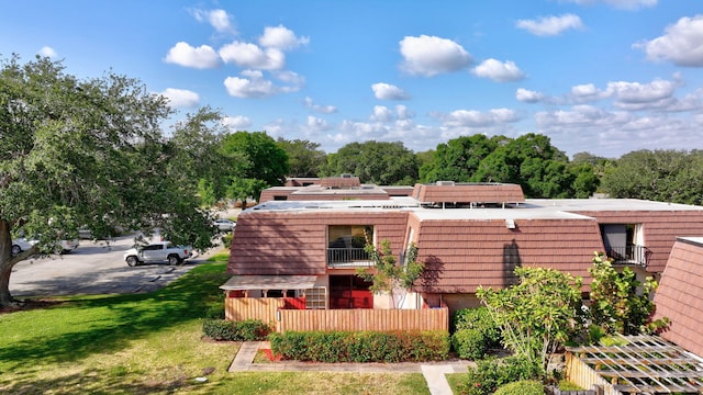 exterior space featuring brick siding, a balcony, and a yard