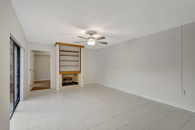 unfurnished living room featuring light tile patterned floors, baseboards, ceiling fan, and a textured ceiling
