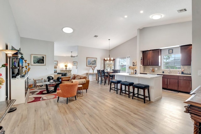 living room featuring light wood-style floors, high vaulted ceiling, and an inviting chandelier